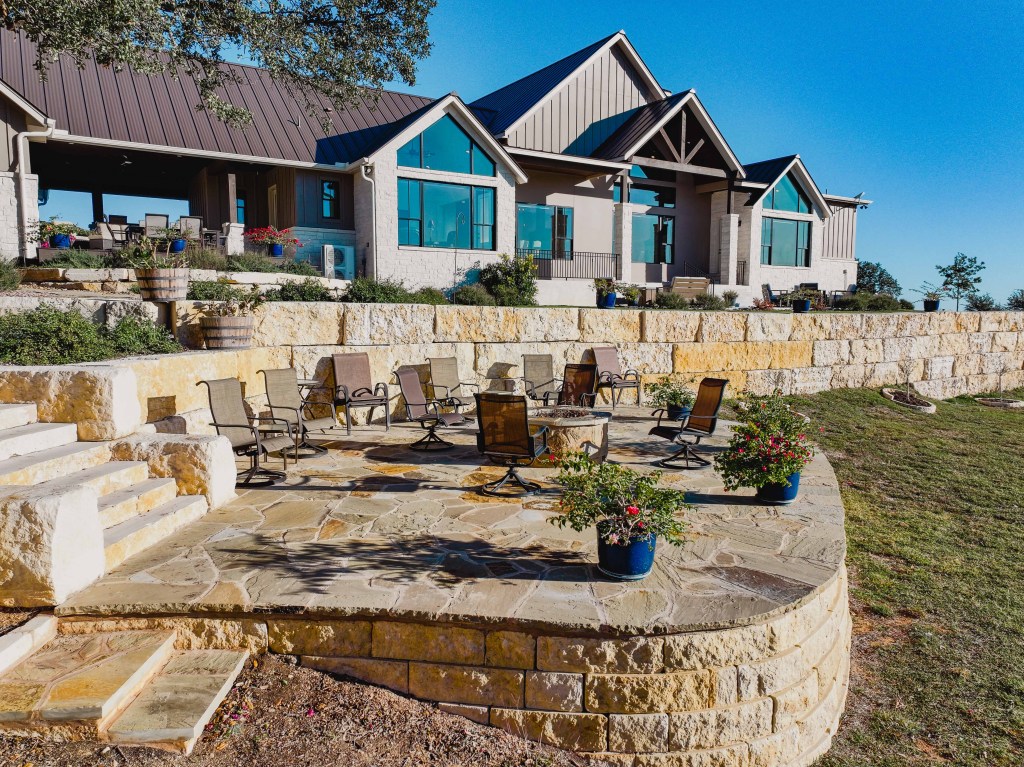 Stone patio and limestone walls behind a custom home